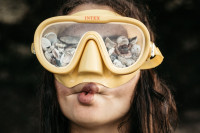Frau trägt gelbe Taucherbrille gefüllt mit Steinen
