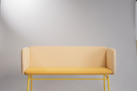 Gelbes Sofa steht vor grauer Wand