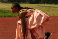 A black person in starting position on a race track.